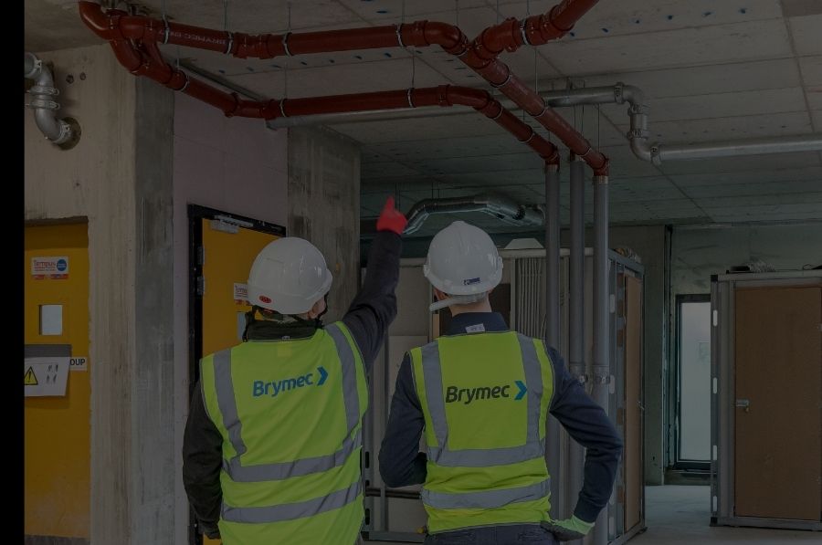 two brymec employees in high vis observing brymec cast iron installed on site